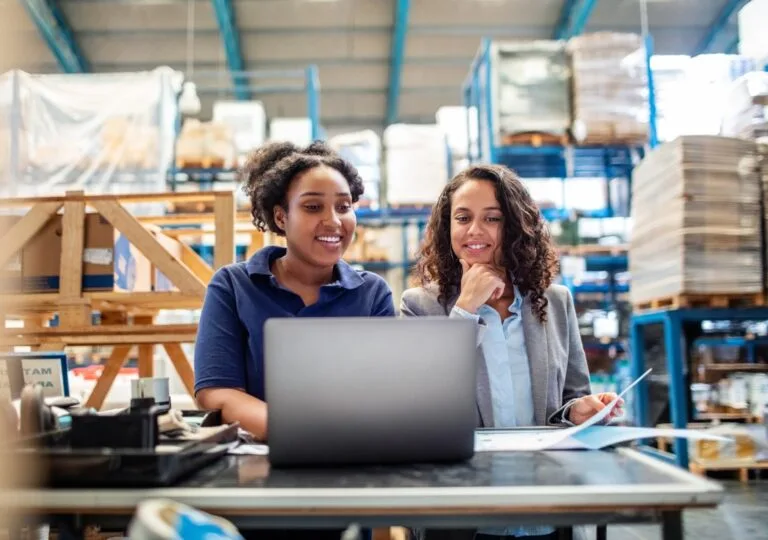Warehouse employees using laptop in distribution center